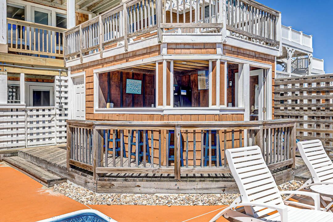 A multi-level wooden building with balconies, a pool area, and outdoor seating.