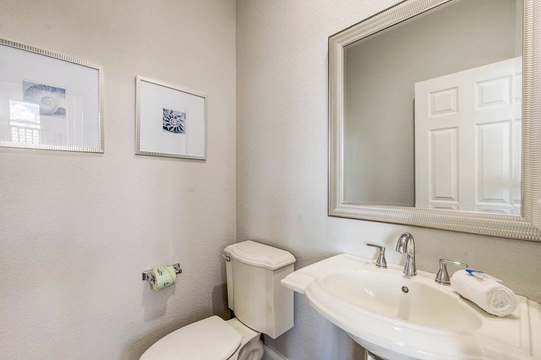 Une salle de bain avec des toilettes, un lavabo et un miroir. Des tableaux encadrés ornent le mur.