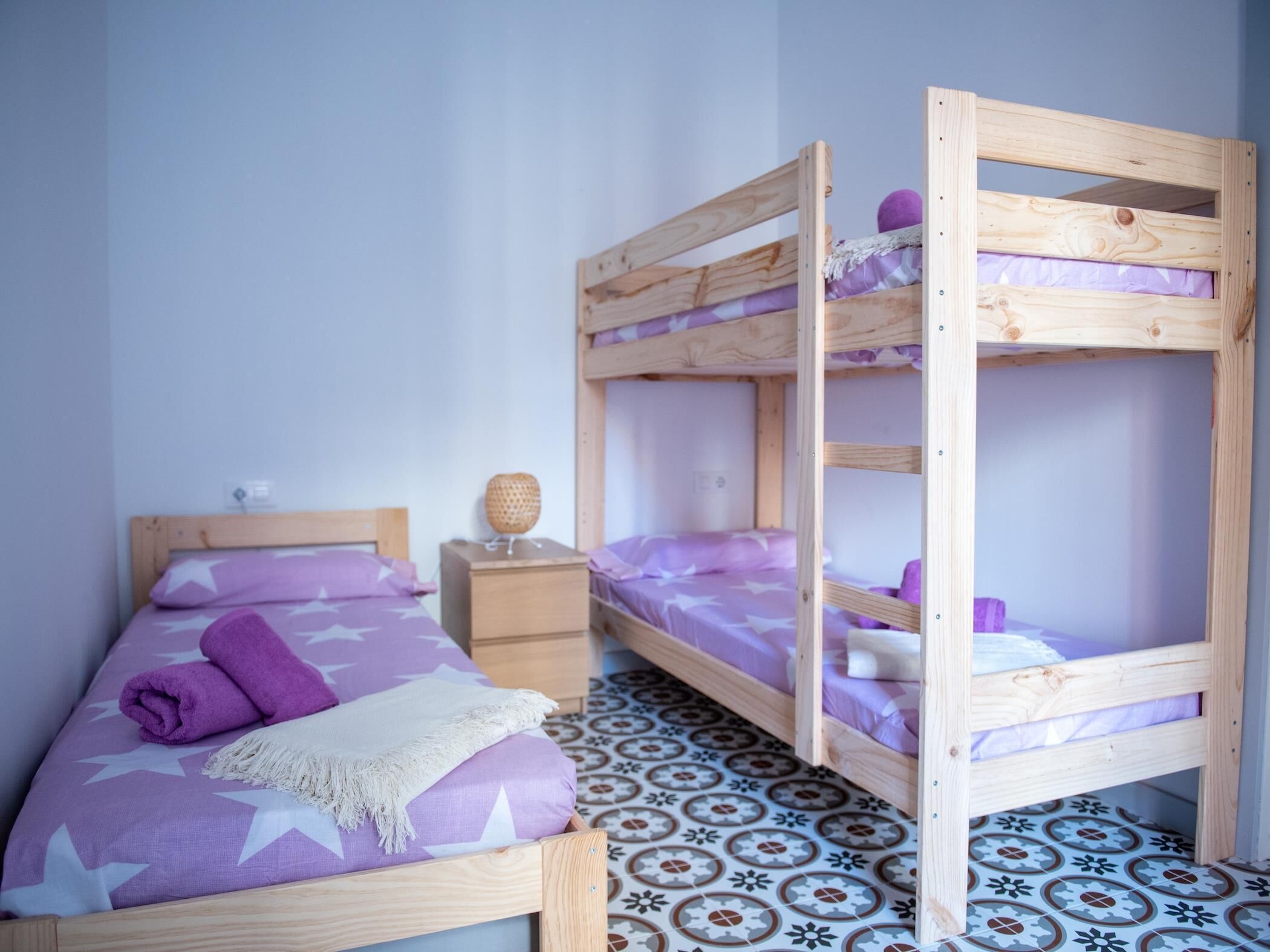 Een kamer met een enkel bed, een nachtkastje en een stapelbed.