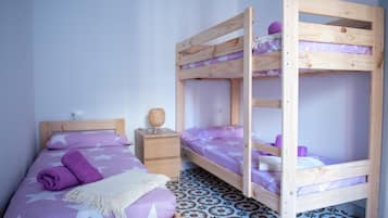 Een kamer met een enkel bed, een nachtkastje en een stapelbed.