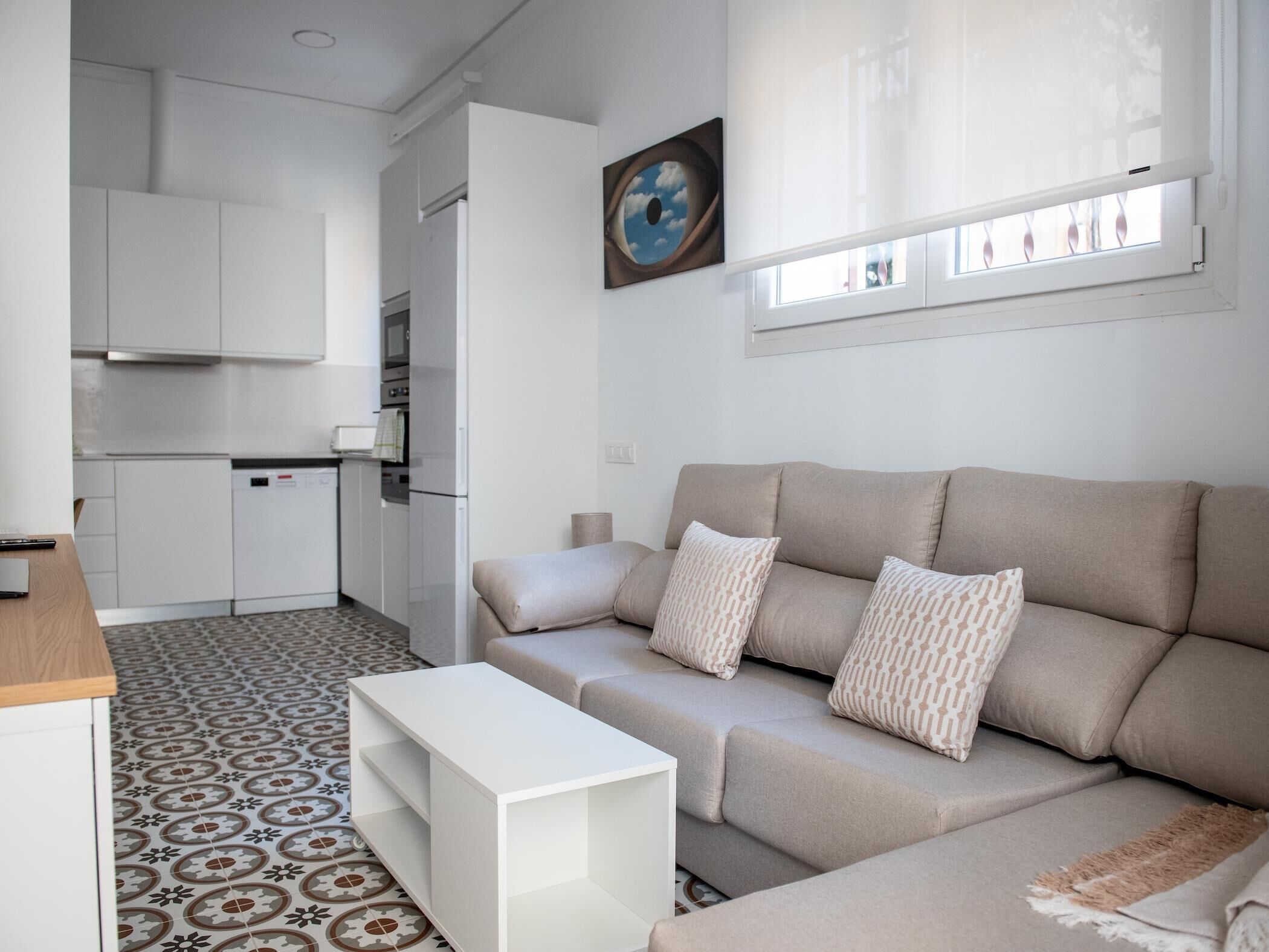 Ein modernes Wohnzimmer mit einem beigefarbenen Sofa, einem weißen Couchtisch und einem Boden mit Muster.