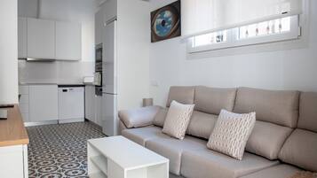 Ein modernes Wohnzimmer mit einem beigefarbenen Sofa, einem weißen Couchtisch und einem Boden mit Muster.