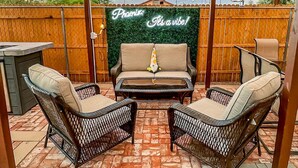 An outdoor patio with wicker furniture, a green wall with 'Prairie' and 'It's a vibe!' text, and a wooden fence in the background.