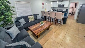 A modern living room with a sofa set, a wooden coffee table, and a dining area with chairs.