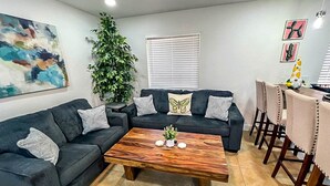 A living room with a sectional sofa, a coffee table, and a dining area with chairs.
