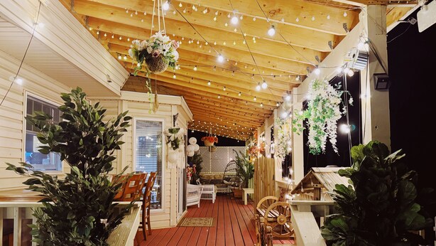 A wooden deck with string lights, potted plants, and outdoor furniture. - Pocono Escape with huge Pool HOT TUB,GAMEROOM,FIREPIT,near Camelback & Kalahari (Stroudsburg)