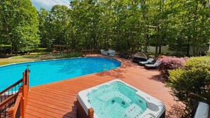 A swimming pool with a wooden deck, lounge chairs, and a hot tub. - Pocono Escape with huge Pool HOT TUB,GAMEROOM,FIREPIT,near Camelback & Kalahari (Stroudsburg)