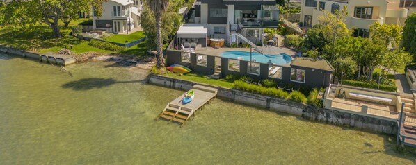 A modern house with a swimming pool, a dock, and a hot tub.