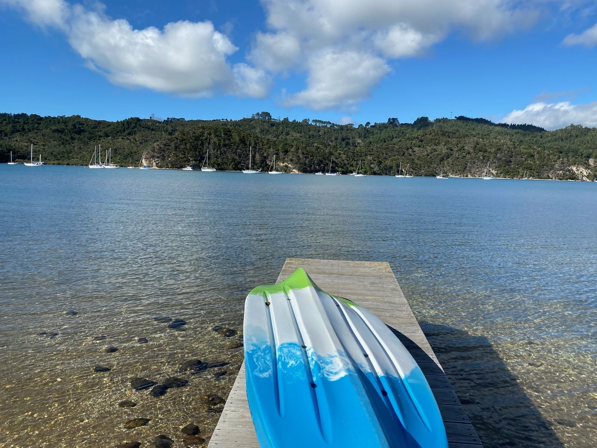 Vista despejada de un muelle de madera con un kayak azul y blanco.