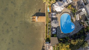 An aerial view of a resort with a swimming pool, sun loungers, and a wooden deck. - Oceans 88 Whitianga Coastal Accommodation Suites (Whitianga)
