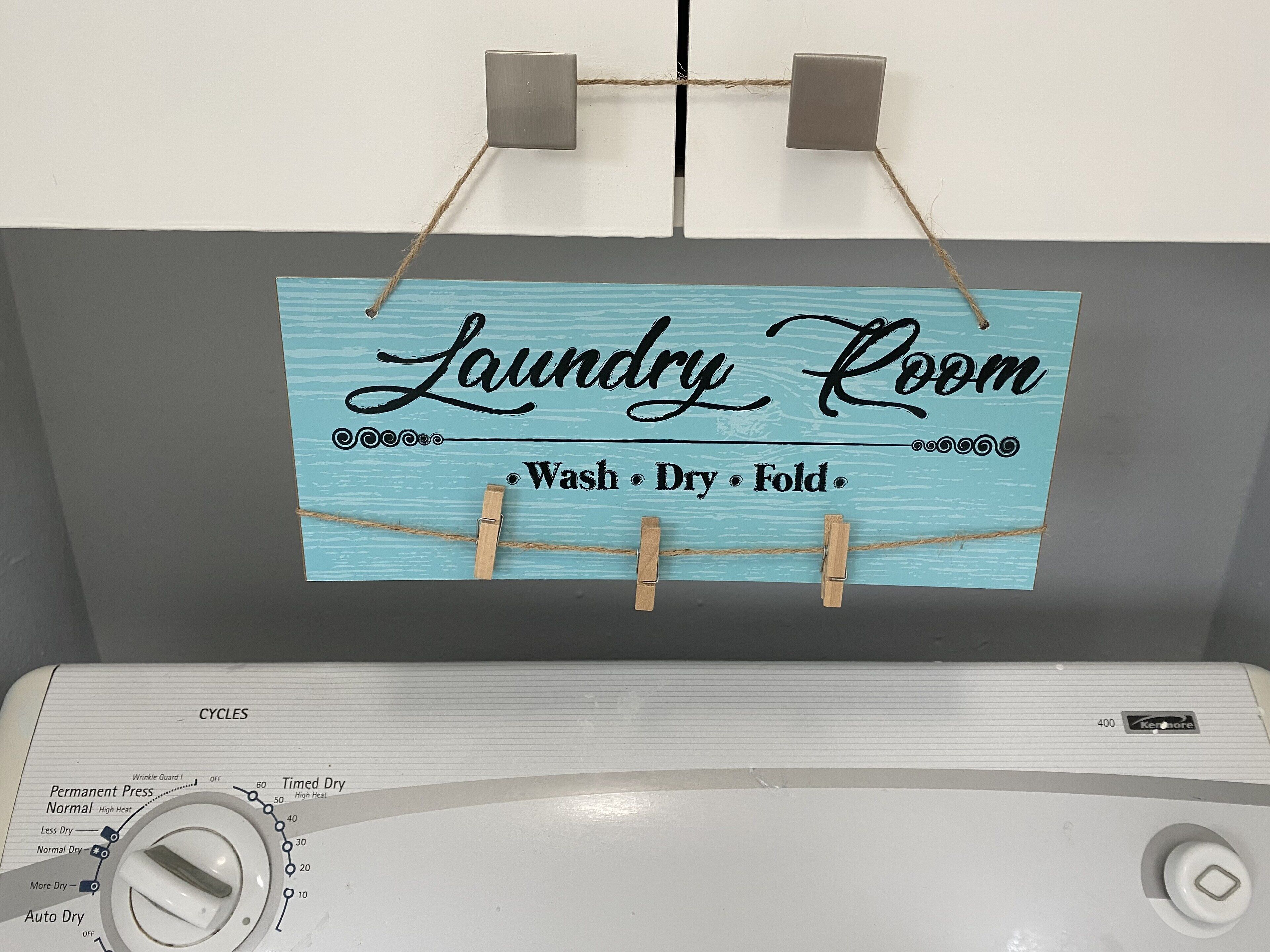Un panneau indiquant l’emplacement de la buanderie, avec un lave-linge en dessous.
