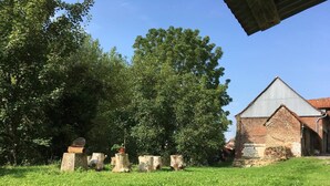 A grassy area with a brick building and trees. - Charming Rustic 2 bedroom annex cottage (Mouriez)