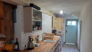 A kitchen with wooden countertops, a kettle, a wine bottle, and a sink. - Charming Rustic 2 bedroom annex cottage (Mouriez)