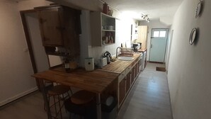 A narrow kitchen with a wooden countertop, a sink, and a stove. There are cabinets and a window above the sink. - Charming Rustic 2 bedroom annex cottage (Mouriez)