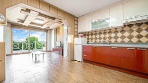 Una cocina moderna con armarios de madera, un refrigerador de acero inoxidable y un amplio ventanal con vistas a un balcón.
