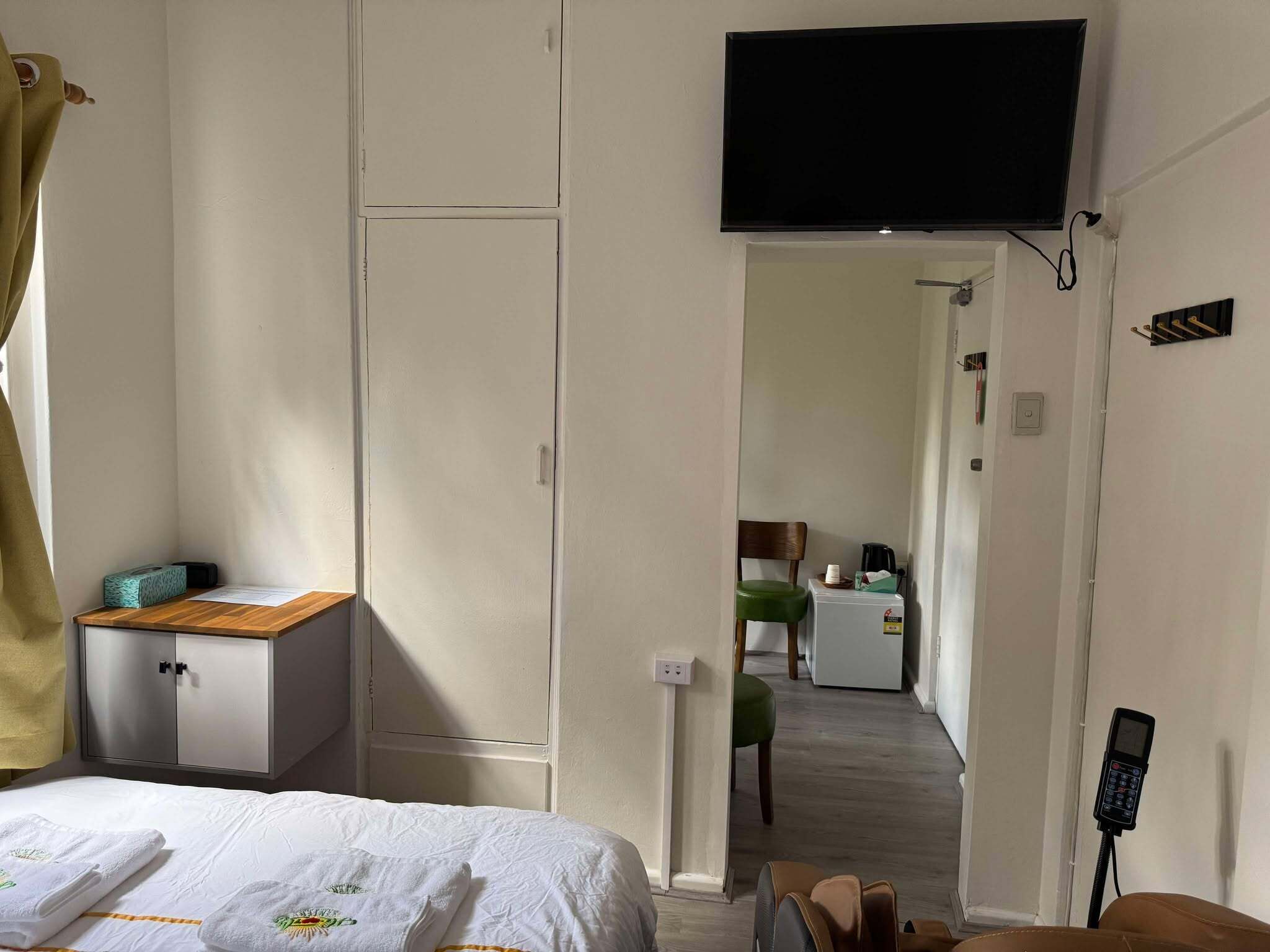 Habitación de hotel con cama, escritorio, silla, televisor y un pasillo que conduce a una kitchenette.