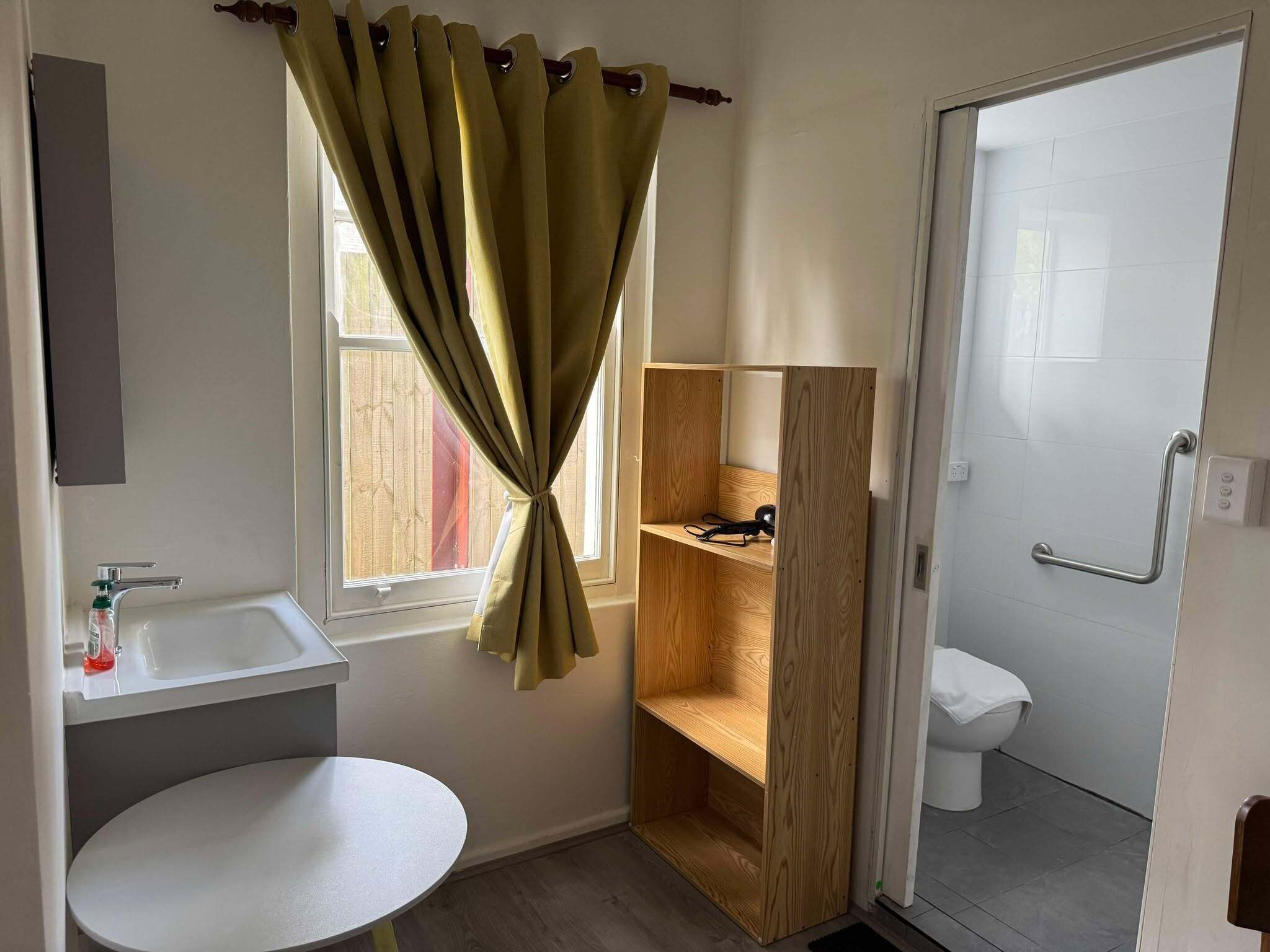 Une salle de bain avec un lavabo, une étagère en bois et des toilettes.