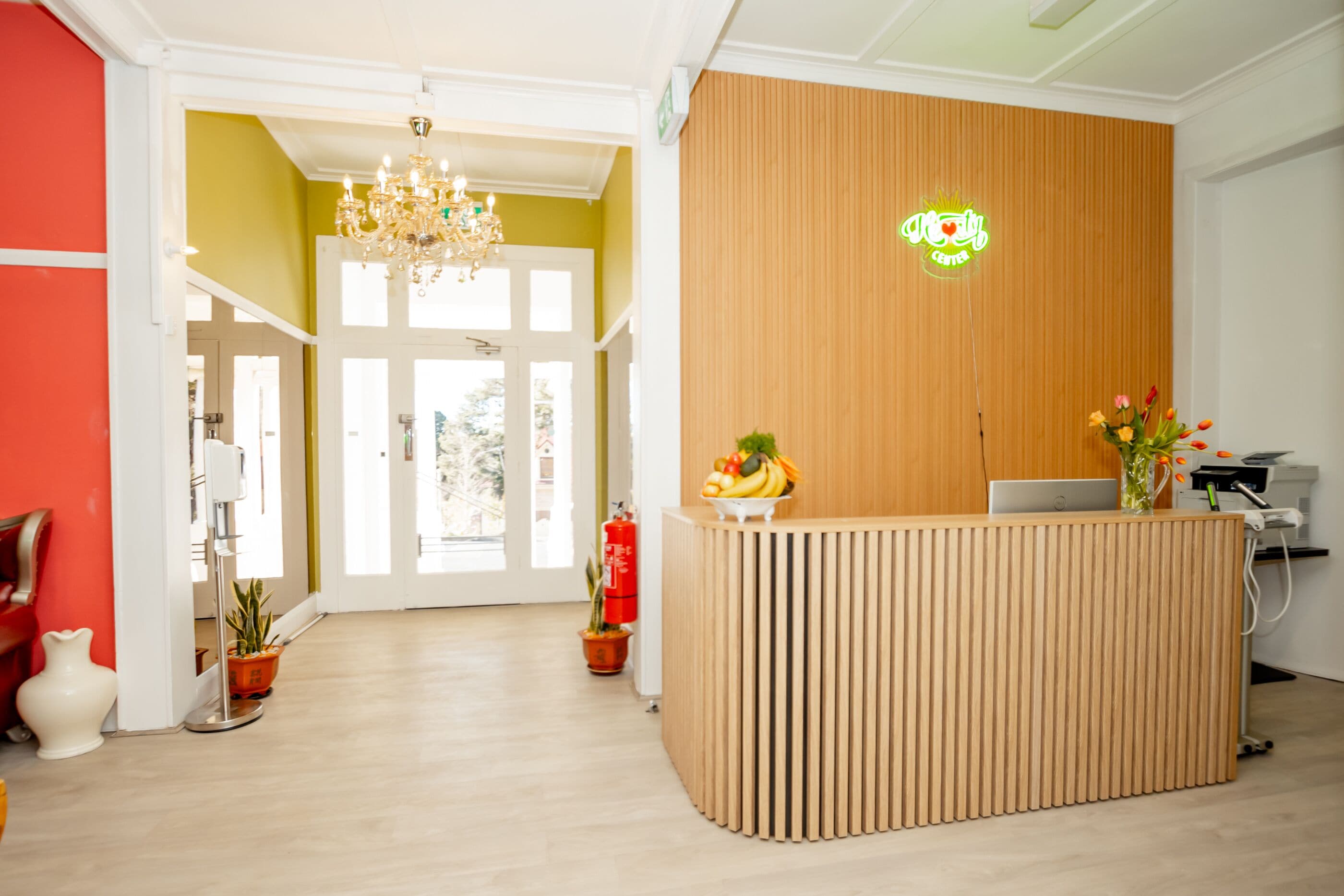 Un mostrador de recepción con detalles de madera, un candelabro y un letrero de neón arriba.