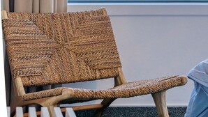 A wicker chair by a window with a view of the ocean. - Esplanade Apartments (Dunedin)