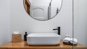 A bathroom with a white sink, a round mirror, and a wooden vanity.