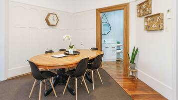 A dining area with a wooden table, black chairs, a clock, and decorative wall art.