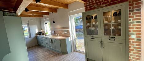 A kitchen with wooden beams, a large island with a sink, and a brick wall.