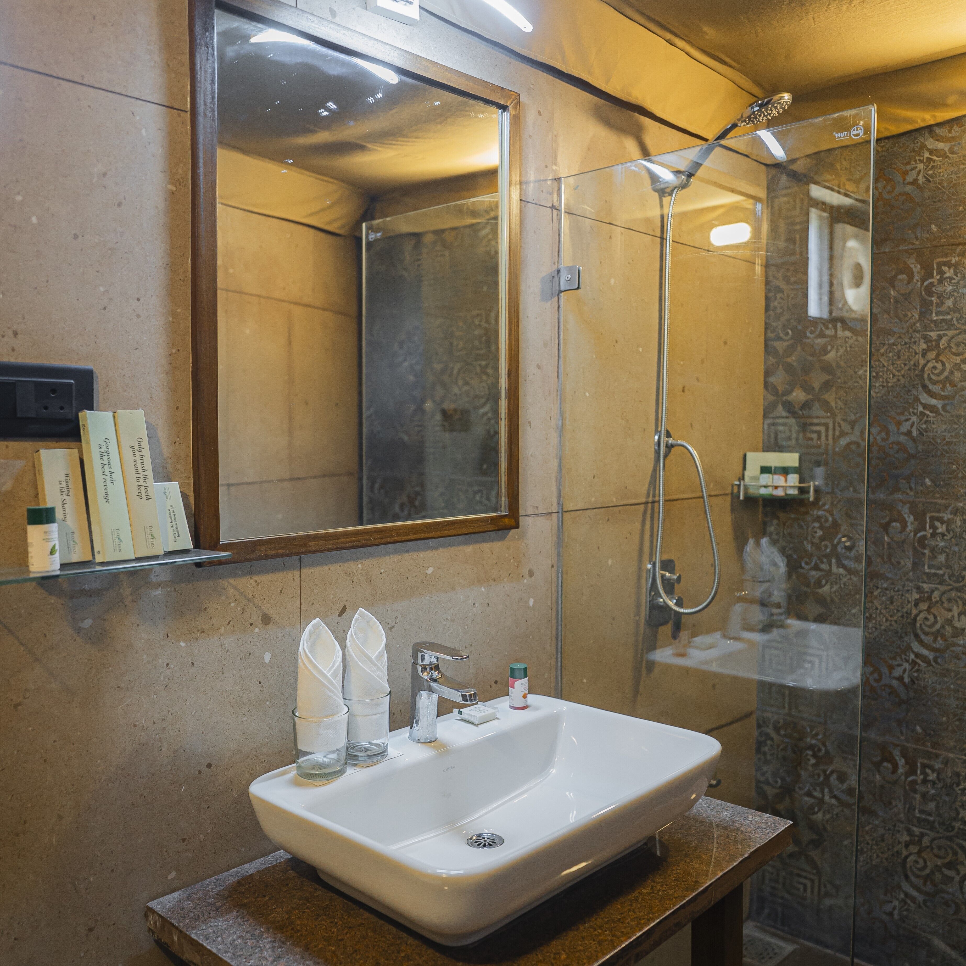 A bathroom with a glass-enclosed shower, a sink with a mirror above it, and toiletries on the counter.
