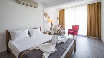 A hotel room with a bed, a chair, a lamp, and a window with curtains.