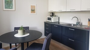 Une cuisine moderne avec une table à manger ronde, des meubles de couleur sombre et un luminaire suspendu.