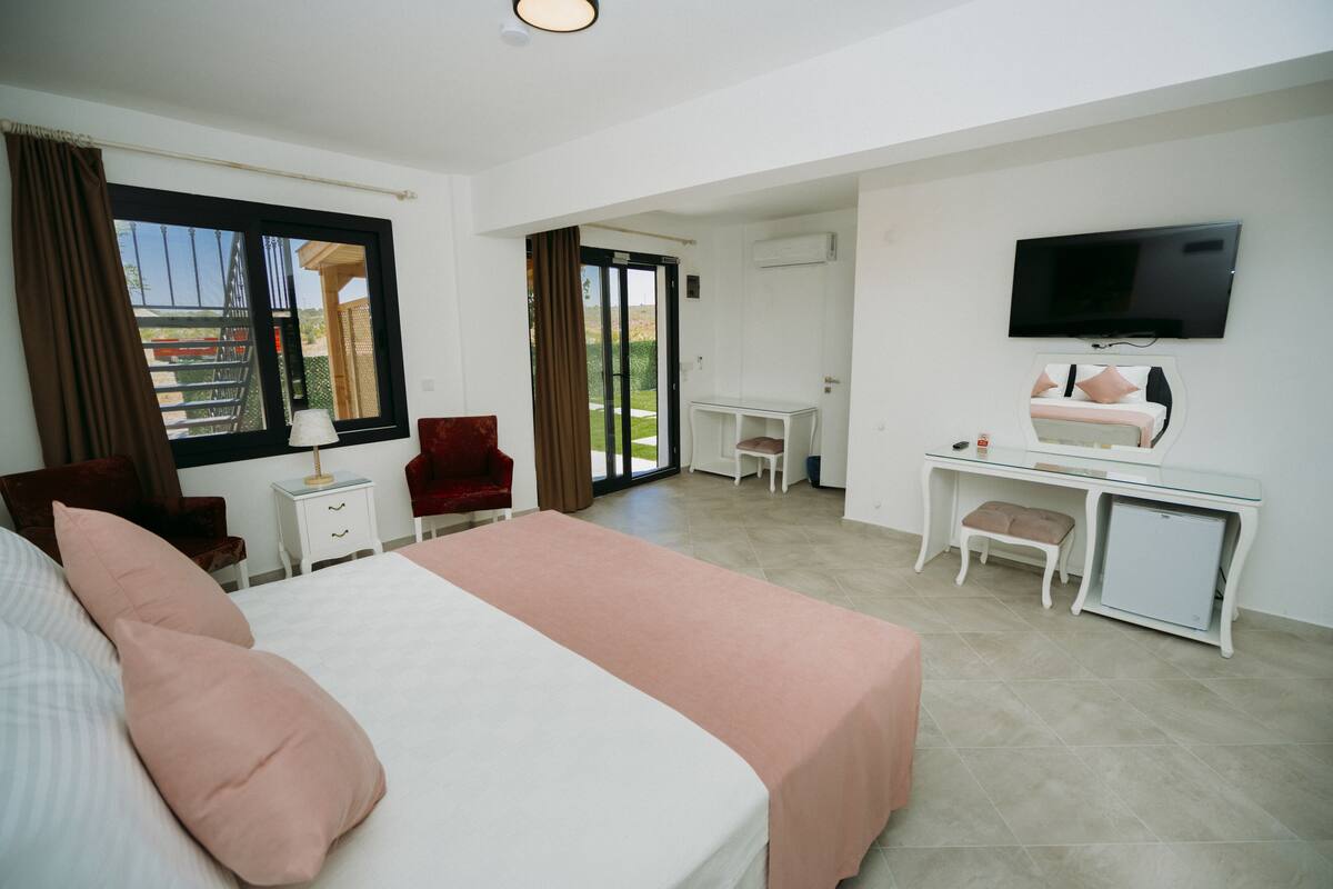 A hotel room with a bed, desk, chair, TV, and a balcony view.