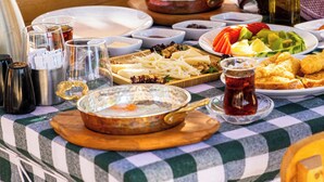 Een tafel gedekt met verschillende gerechten, waaronder een kom soep, een bord met gesneden groenten en een fles olijfolie.