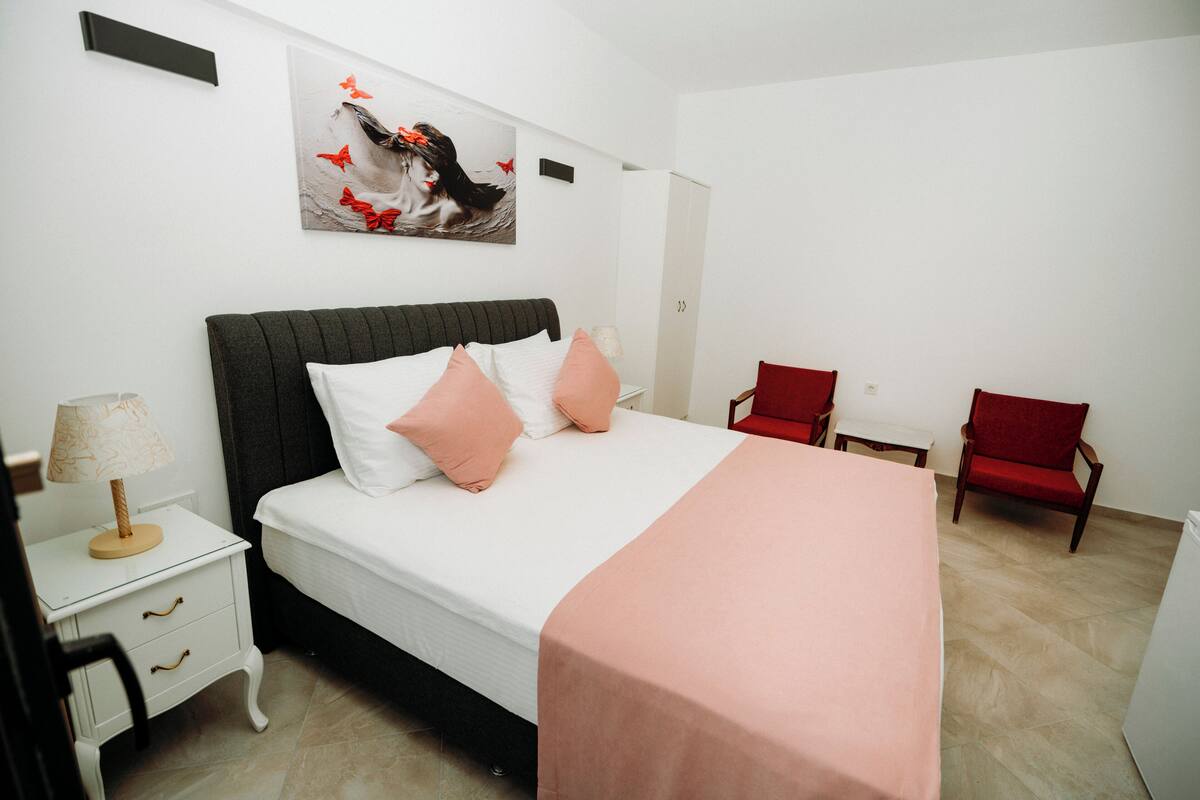 A neatly arranged bedroom with a bed, bedside table, and a chair.