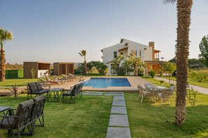 A modern house with a swimming pool, outdoor seating, and a well-maintained lawn.