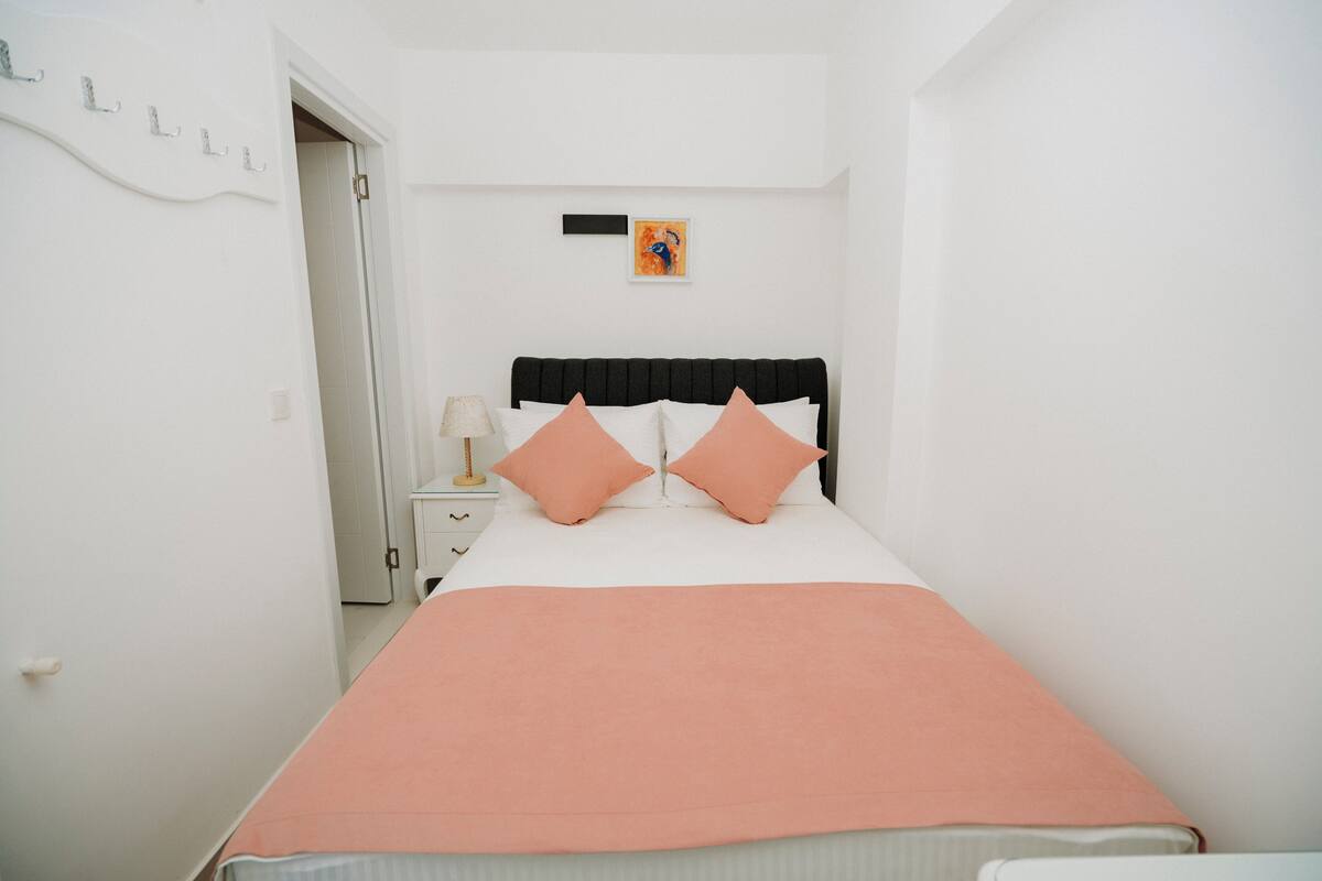 A bedroom with a bed, a nightstand, a lamp, and a wall-mounted artwork.