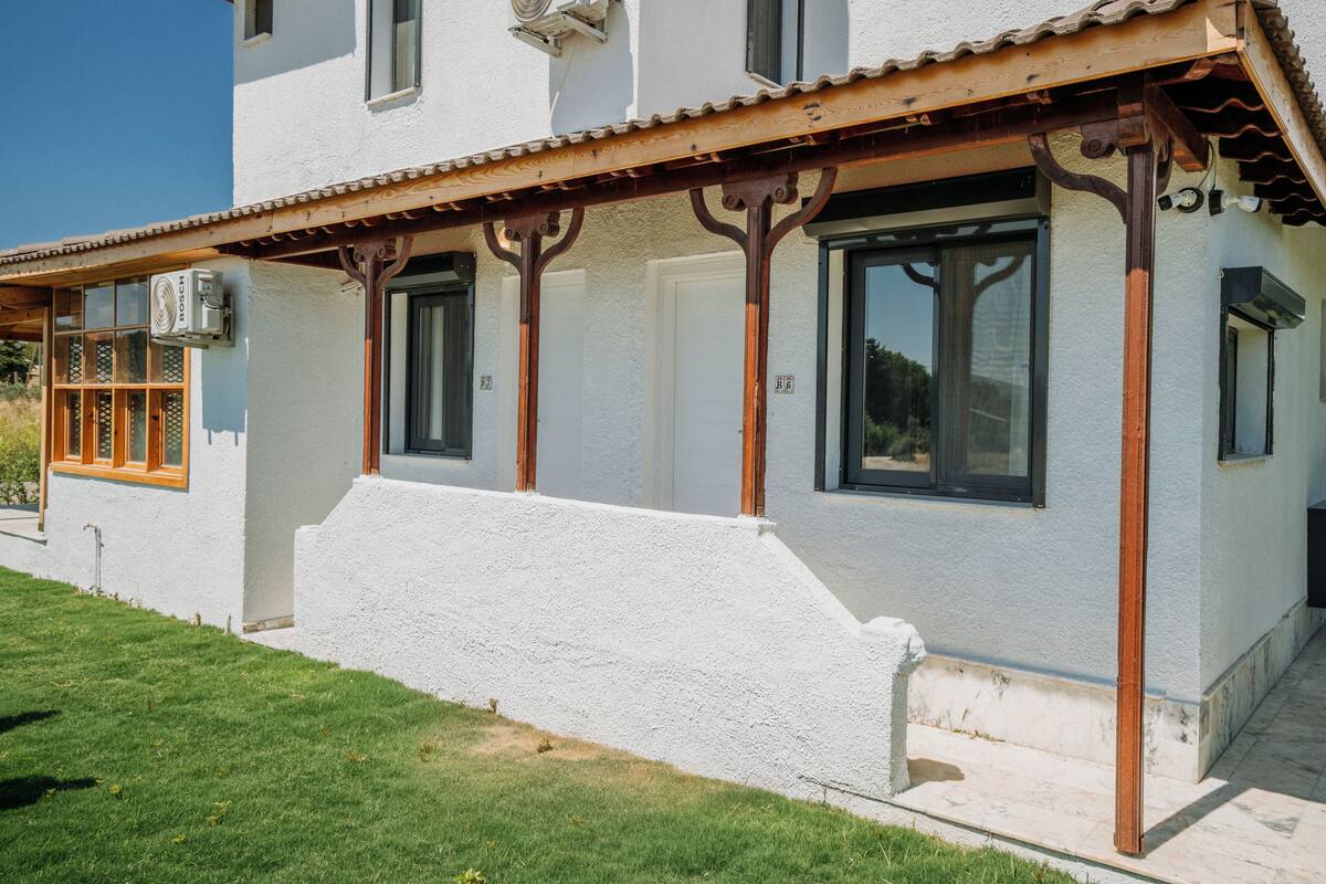 A white building with a wooden porch and large windows.