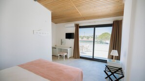 Een slaapkamer met een bed, een bureau, een stoel, een televisie en uitzicht op de omgeving.