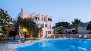 A modern two-story building with a swimming pool, lounge chairs, and a stone wall. - Villa Luisa Exclusive Residences (Monemvasia)