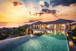 A modern house with a swimming pool, large windows, and a balcony overlooking a scenic view.