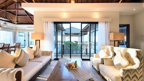 A spacious living room with a wooden ceiling, large windows, and a view of a traditional building. - Karang Saujana Estate (Kutuh)