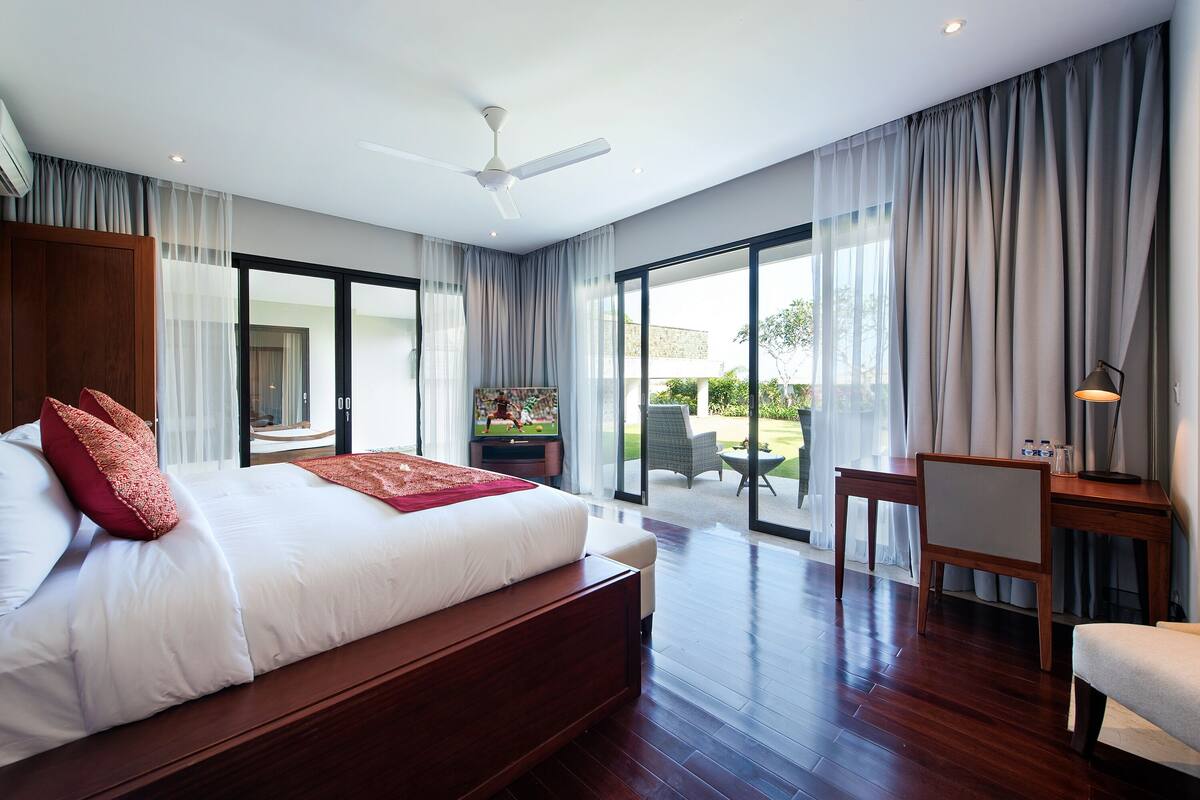 A modern bedroom with a large bed, a desk, and a chair.
