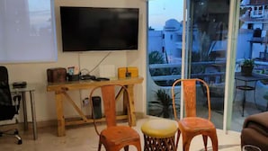 Un salon doté d’un téléviseur à écran plat, de meubles en bois et d’une porte vitrée donnant sur un espace extérieur.