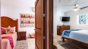 Une chambre à coucher avec un lit en bois, une télévision et un mur décoré de motifs colorés.
