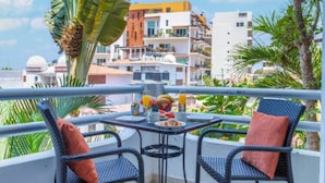 Un balcon avec deux fauteuils en osier et une table dressée pour le petit-déjeuner.