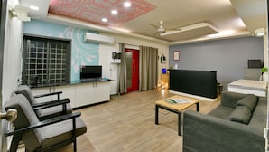 A modern living room with a sofa, chairs, a coffee table, and a TV. - Hotel Admire Inn Sector-51 by ASPL (Noida)