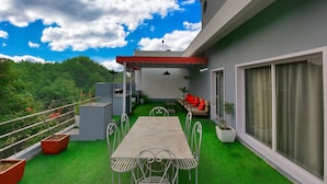 A rooftop terrace with a table and chairs, a sofa, and potted plants. - Hotel Admire Inn Sector-51 by ASPL (Noida)