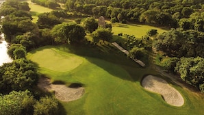 A golf course with sand bunkers, a water hazard, and a city skyline in the background. - Hotel Admire Inn Sector-51 by ASPL (Noida)