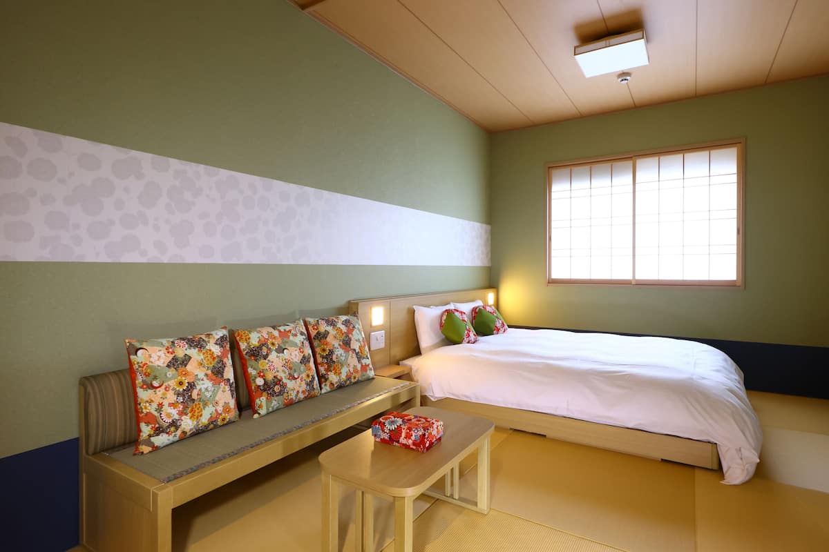 Ein Zimmer mit einem Bett, einer Bank und einem kleinen Tisch.