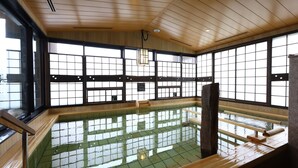 Un onsen japonais traditionnel, avec un intérieur en bois, de grandes fenêtres et un sol carrelé.
