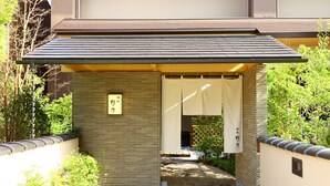 Une entrée de style japonais traditionnel, avec un chemin de pierres menant à une zone abritée.