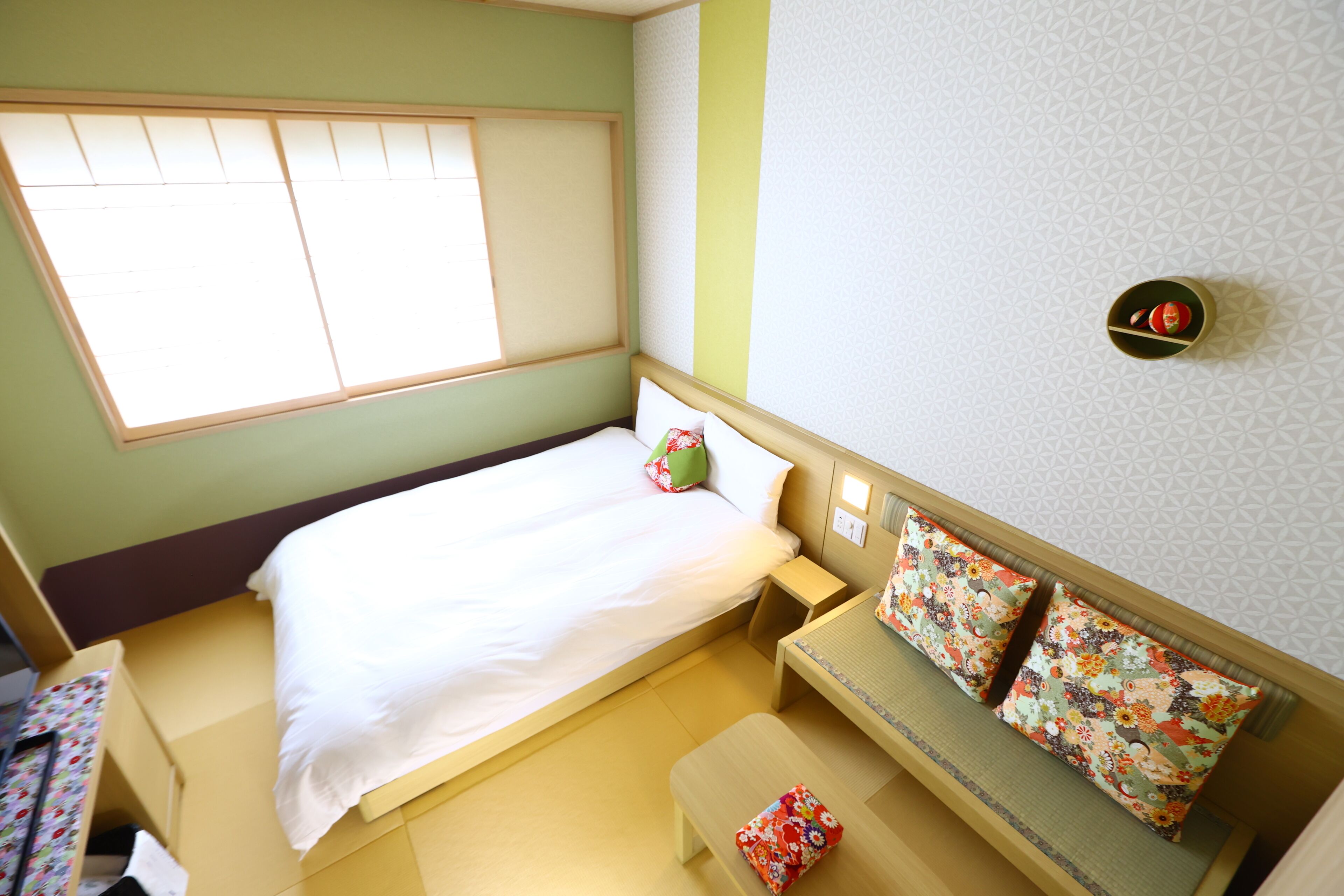 A small, neatly arranged room with a bed, a bench, and a small table.